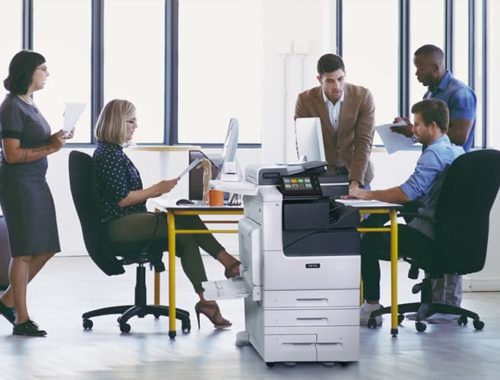Teamarbeit in einem Büro mit bedruckten Papieren und dem Farb-Multifunktionsdrucker Xerox® VersaLink® C7100 Series
